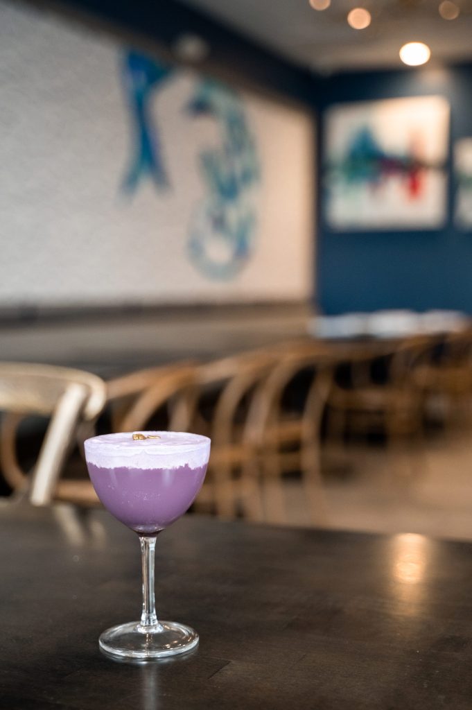 Purple cocktail on a table inside Gather.
