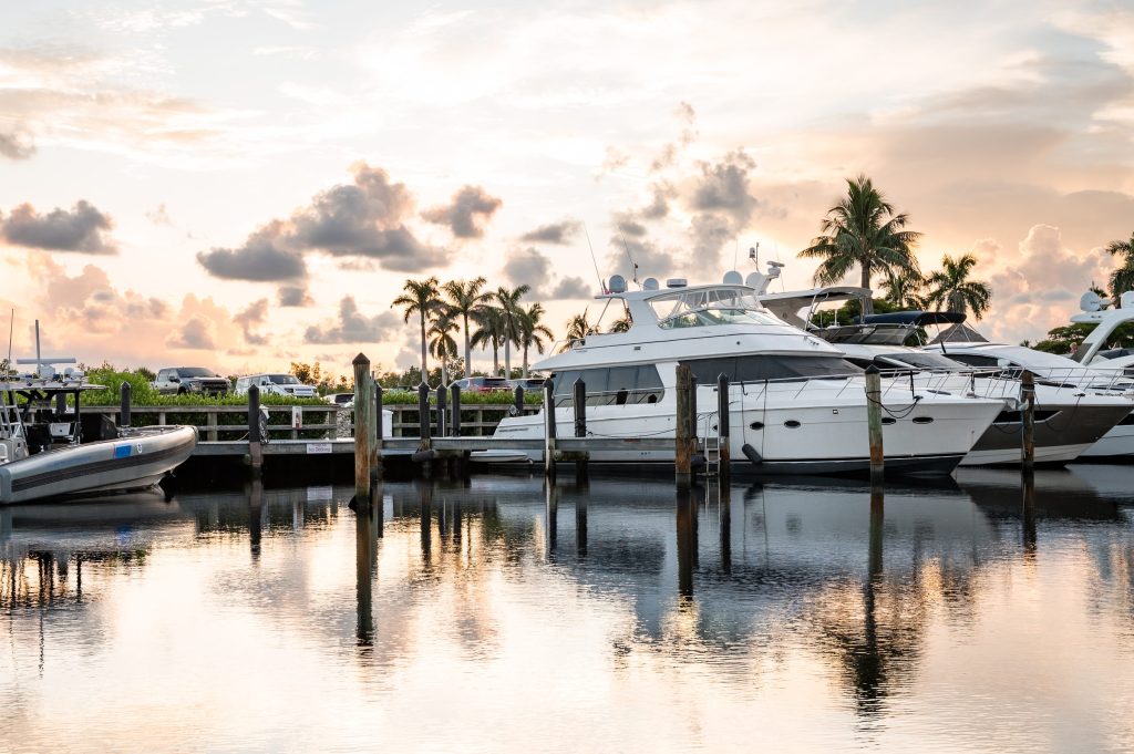 Yachts at Tarpon Point Marina at dusk with palm trees reflected in the water.