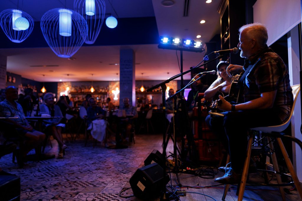 Guitarist performing live at Gather as guests watch from the dining room.