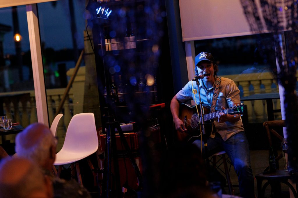 Guitarist singing during a live performance at Gather.